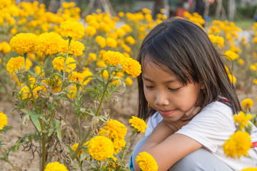 Adorable girl smiling on marigold flowers field. Natural light.