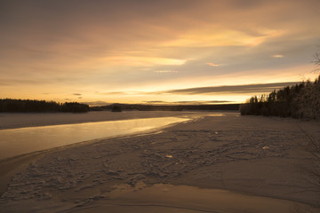 A partly frozen river and a sunset with snow