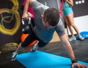 Young man lifting dumbbell and kettlebell at the fitness center