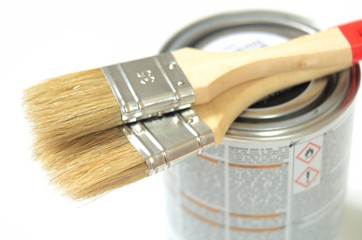Paint brushes lying on the can of paint on a white