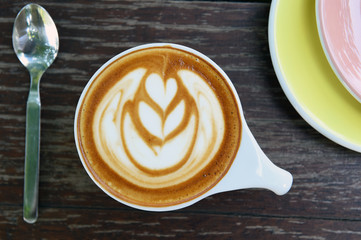 cup of latte art coffee on wooden background