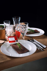 Decorated Christmas holiday table ready for dinner. Beautifully decorated table set with candles, spruce twigs, plates and serviettes for event in the restaurant.