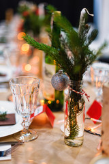 Decorated Christmas holiday table ready for dinner. Beautifully decorated table set with candles, spruce twigs, plates and serviettes for event in the restaurant.