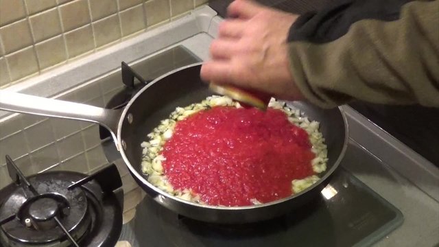 putting tomato for italian pasta sauce