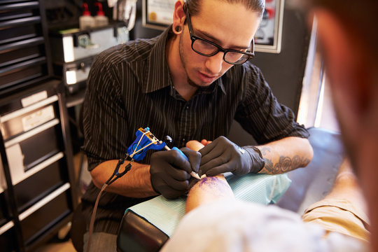 Tattoo Artist Working On Design For Male Client