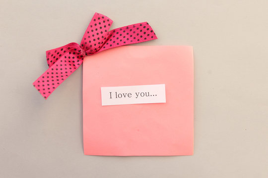 Happy Valentine's day concept - ribbon and love message tags on pink background