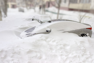Car covered with snow among snowdrifts