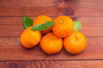 Several mandarin oranges on a dark wooden surface
