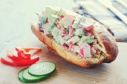 Crab salad sandwich on wooden cutting board, toned image