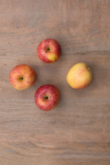 Four red apples on a wooden background