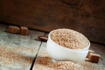 Brown sugar in a white porcelain bowl on the old wooden backgrou