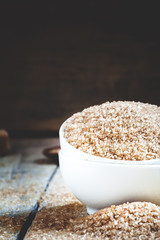 Brown sugar in a white porcelain bowl on the old wooden backgrou