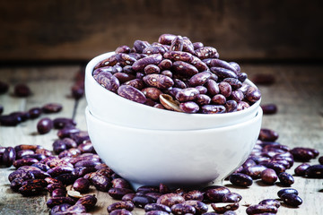 Purple-brown dry beans in a white porcelain bowl on the old wood
