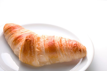 Croissant auf einem Teller vor hellem Hintergrund