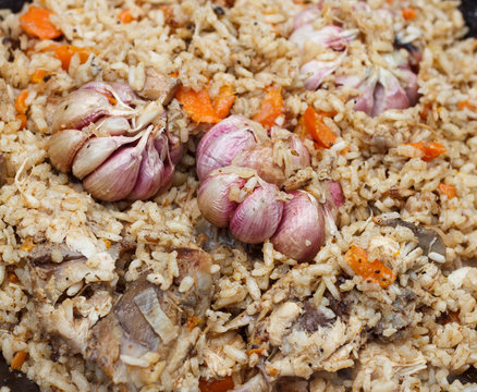 The preparation of traditional Uzbek pilaf with meat, carrots, garlic and spices