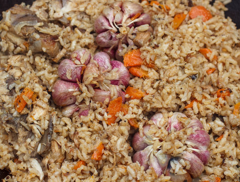 The preparation of traditional Uzbek pilaf with meat, carrots, garlic and spices