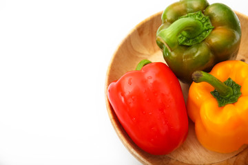 fresh bell peppers in wooden bowl on white background
