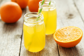 Obraz na płótnie Canvas Orange juice in bottle on grey wooden background