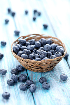 Tasty blueberries in basket on a blue wooden table