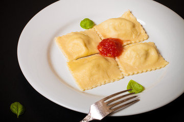 Russian ravioli - pelmeni with tomato sauce and basil on a white
