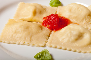 Russian ravioli - pelmeni with tomato sauce and basil on a white