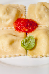 Russian ravioli - pelmeni with tomato sauce and basil on a white