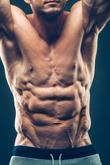 Strong Athletic Man Fitness Model Torso showing six pack abs. isolated on black background with copyspace