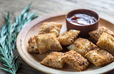 Plate with fried ravioli on the wooden board