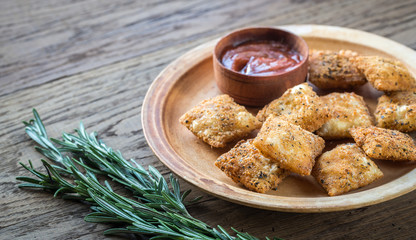 Plate with fried ravioli on the wooden board