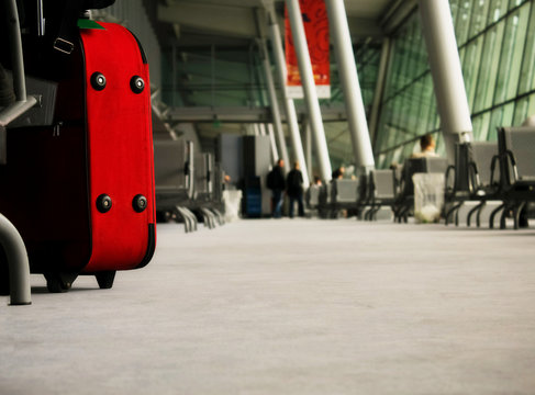 Red suitcase in a waiting area at the airport (perspective shot)
