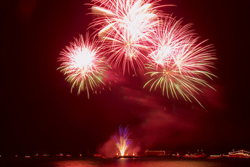 Beautiful colorful red and orange holiday fireworks on the black sky background