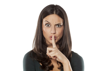 Naklejka premium angry young holding a finger in front of her mouth