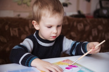Cute little boy painting with brush