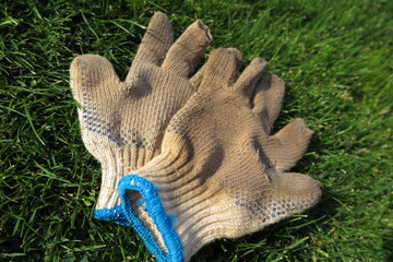 Dirty and worn-out gardening textile gloves on the mown lawn after hard work in the autumn garden