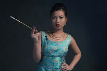 Obraz premium Wealthy Asian woman in retro 1940 dress smokes cigaret.