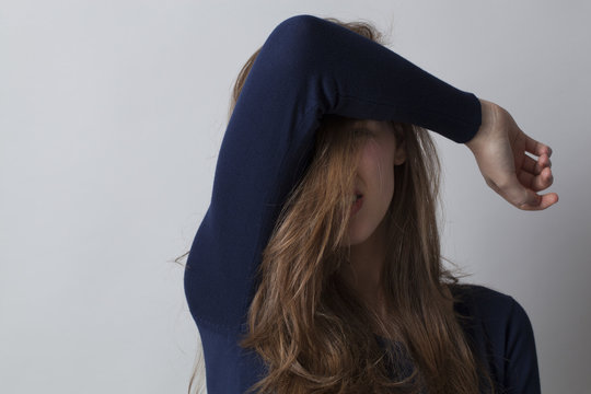 haircare concept - beautiful young woman hiding her face with her hair and arm for beauty regret,studio shot