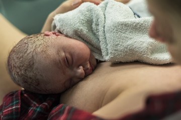 Healthy newborn baby, seconds after birth, resting on mother