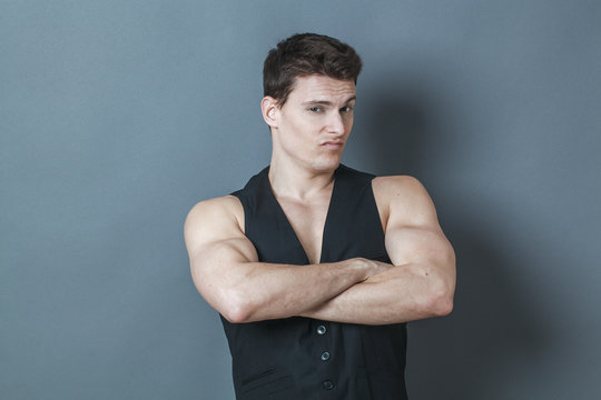 muscle concept - suspicious young man crossing his big muscular arms showing his arrogant strength and male power,studio shot,low contrast effect