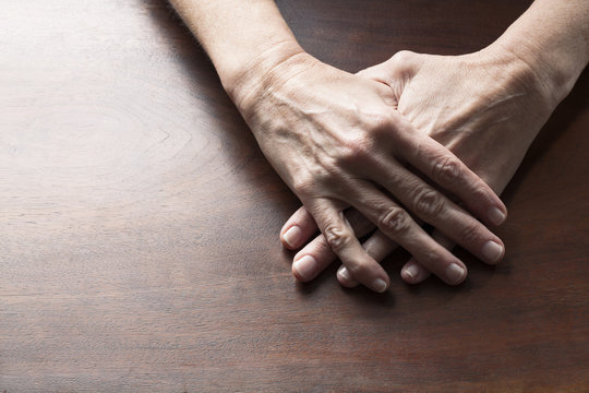 talking hands concept - female hands set together for solitude or loneliness on wooden table,studio shot