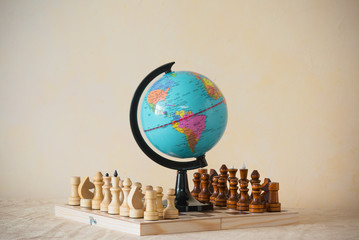 Closeup beautiful view of small miniature world globe model standing on chess wooden board