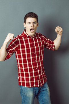 muscle concept - shouting young man with arms raised expressing his exasperation and frustration,studio shot,low contrast effect