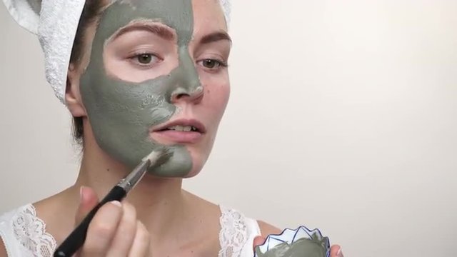 Woman applying with brush clay mud mask to her face 4K