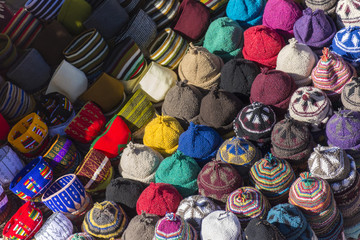Fototapeta na wymiar Muslim woman selling hats in a Market stall in the Marrakech sou
