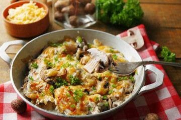 Fototapeta na wymiar Roasted mushrooms, chicken and cheese gratin in pan, on wooden background