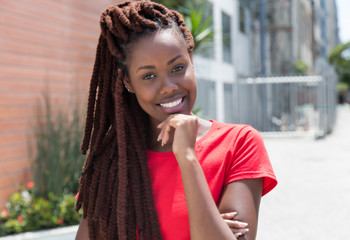 Lachende Afrikanerin mit Rastalocken im roten Shirt