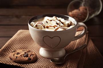 Mug of hot chocolate with marshmallows, on wooden background