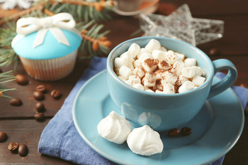 Mug of hot chocolate with marshmallows, fir tree branch on wooden background