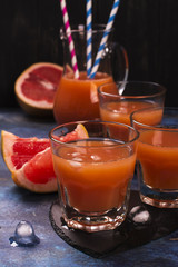 Fresh pomelo juice with ice over dark wooden background. Selective focus