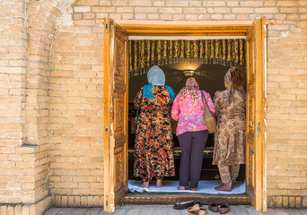 Uzbekistan, Samarkand, local faithful in prayer in the St Daniel mausoleum - obrazy, fototapety, plakaty