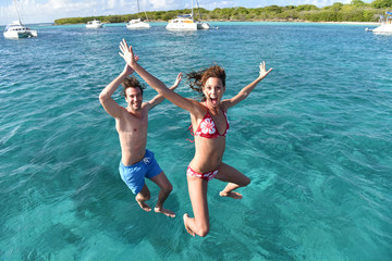 Cheerful couple jumping into water from boat